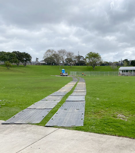 Two tracks of ground protection mats on a grass field